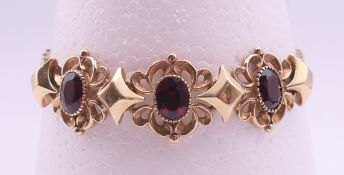 A 9 ct gold bracelet with three large garnets. 20 cm long. 21.5 grammes total weight.