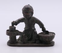 A bronze model of a boy cooking. 7.5 cm long.