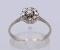 An 18 ct white gold and diamond flowerhead ring. Ring size P. 2.1 grammes total weight.