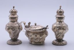A silver cruet set comprising mustard pot and spoon and two peppers. The mustard pot 9 cm long. 138.