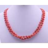 A string of red coral beads with a 9 ct gold clasp. 83 cm long.