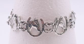 A silver horseshoe and horses head bracelet. 18 cm long.