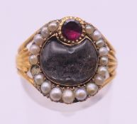 An unmarked antique gold, seed pearl and garnet mourning ring. Ring size N.