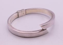 A hinged silver bangle. 5.5 cm inner diameter.