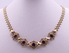A 9 ct gold necklace with five large garnets with unusual-designed clasp. 48 cm long.