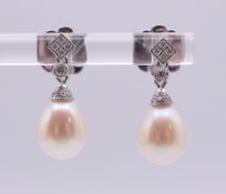 A pair of 18 ct white gold, pearl and diamond earrings. Each 1.8 cm high.