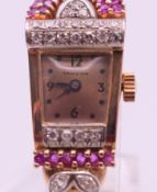 A 14 ct gold, ruby and diamond ladies' wristwatch. 1.7 cm wide. 17.4 grammes total weight.