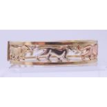 A 9 ct tri-colour gold bangle bracelet with openwork panther decoration. 1.