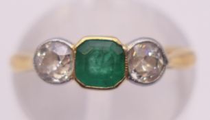 An 18 ct gold, diamond and emerald three-stone ring. Ring size K. 2.3 grammes total weight.