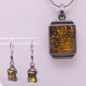 An unmarked silver and amber pendant on a chain and matching earrings. Pendant 3 cm high.