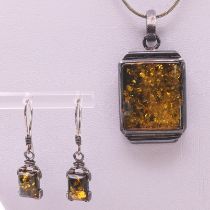 An unmarked silver and amber pendant on a chain and matching earrings. Pendant 3 cm high.