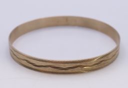 A 9 ct gold metal core bangle. 8 mm high, 6.75 cm internal diameter. 13.3 grammes total weight.