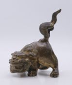 A Chinese antique bronze temple dog scroll weight with traces of gilding. 11.5 cm high.