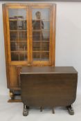An early 20th century glazed oak bookcase and a folding dining table.