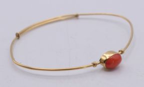 A 18 ct gold and coral bangle. Bangle 1mm high, internal diameter 6.25 cm. 3.