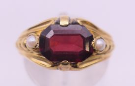 An unmarked gold garnet and pearl ring. Ring size P. 2.5 grammes total weight.