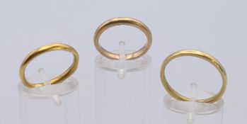 A 9 ct gold wedding band and two other unmarked wedding bands. The former ring size L. 9.