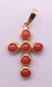 An 18 ct gold coral set cross pendant. 1.75 cm high. 0.5 grammes total weight.