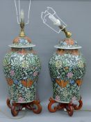 A pair of Chinese black ground porcelain lamps on wooden stands. Each 75 cm high overall.