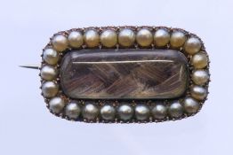A 19th century unmarked seed pearl and hair plait-set mourning brooch. 2.2 cm wide.