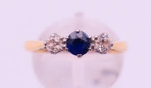 An 18 ct gold diamond and sapphire three-stone ring. Ring size M/N. 2.7 grammes total weight.