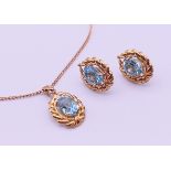 A 9 ct gold pendant on chain and a matching pair of earrings, each set with a blue stone.