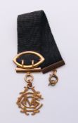 A ribbon-form pendant set with 9 ct gold MCG initials. 14.5 cm high overall. 9.