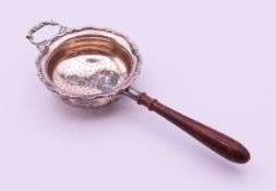 A silver tea strainer with turned wooden handle. 17 cm long. 48.3 grammes total weight.
