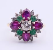 An 18 ct gold, diamond, ruby and emerald flower head ring. Ring size P. 5.2 grammes total weight.