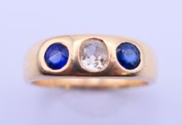 An unmarked gold gypsy set three stone diamond and sapphire ring. Ring size P. 4.