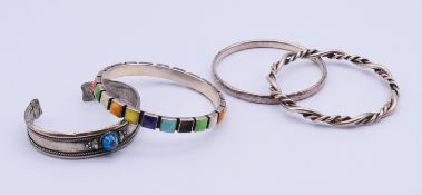 Four silver bangles. Multi-coloured bangle 6.5 cm internal diameter, 0.75 cm high.
