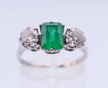A platinum, diamond and emerald three stone ring. Ring size P.