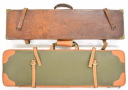 Two shotgun carry cases, one leather and brass bound the other faux leather bound, largest 85cm