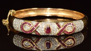 An 18ct gold bangle set with an oval cut ruby of approximately 0.4ct, calibre cut rubies and round