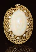 An 18k gold ring set with an opal cabochon surrounded by diamonds, in a lattice setting (setting