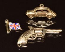 Three 9ct gold charms in the form of an enamel flag, gun and car, 3.3g
