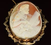 A yellow metal brooch set with a cameo depicting God writing on a scroll with a cherub and clouds,