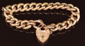 A 9ct rose gold curb link bracelet of alternating smooth and engraved links with heart padlock