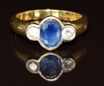 An 18ct gold ring set with an oval cut sapphire of approximately 0.75ct and two diamonds, each