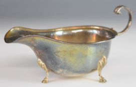 Hallmarked silver sauce boat with beaded edge and scroll handle, raised on three feet, Birmingham