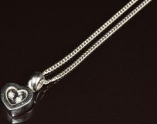 An 18k white gold pendant in the form of a heart set with two floating diamonds (2cm) on 18ct