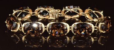 A 9ct gold bracelet set with nine oval cut smoky quartz, 27.3g, 18cm