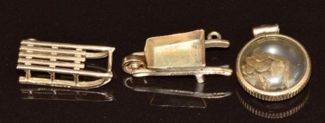 Two 9ct gold charms including sledge and wheelbarrow (2.3g) and a locket set with gold nuggets