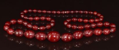 Cherry amber necklace made up of sixty three graduated oval beads, the largest 18.4 x 22.1mm and