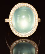 A yellow metal ring set with a chrysoprase cabochon surrounded by diamonds, 14.3g, size L