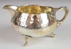 Arts & Crafts Edward VII hallmarked silver milk jug with hammered decoration, raised on three