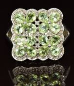A 9k white gold ring set with peridot and diamonds in four flower clusters, 4.6g, size N