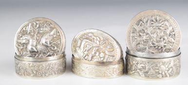Three Chinese, Burmese or similar circular and oval silver trinket pots, with embossed foliate,