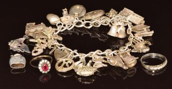 Silver charm bracelet with twenty one charms including acorn, magician's hat, train, ship, church,