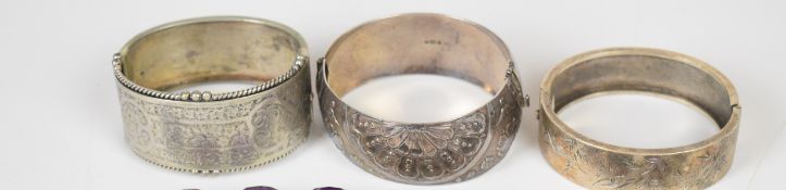 Three silver bangles, one with engraved bird decoration, one engraved foliate decoration and the